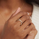 Close-up of a hand wearing two gold rings on a blurred background
