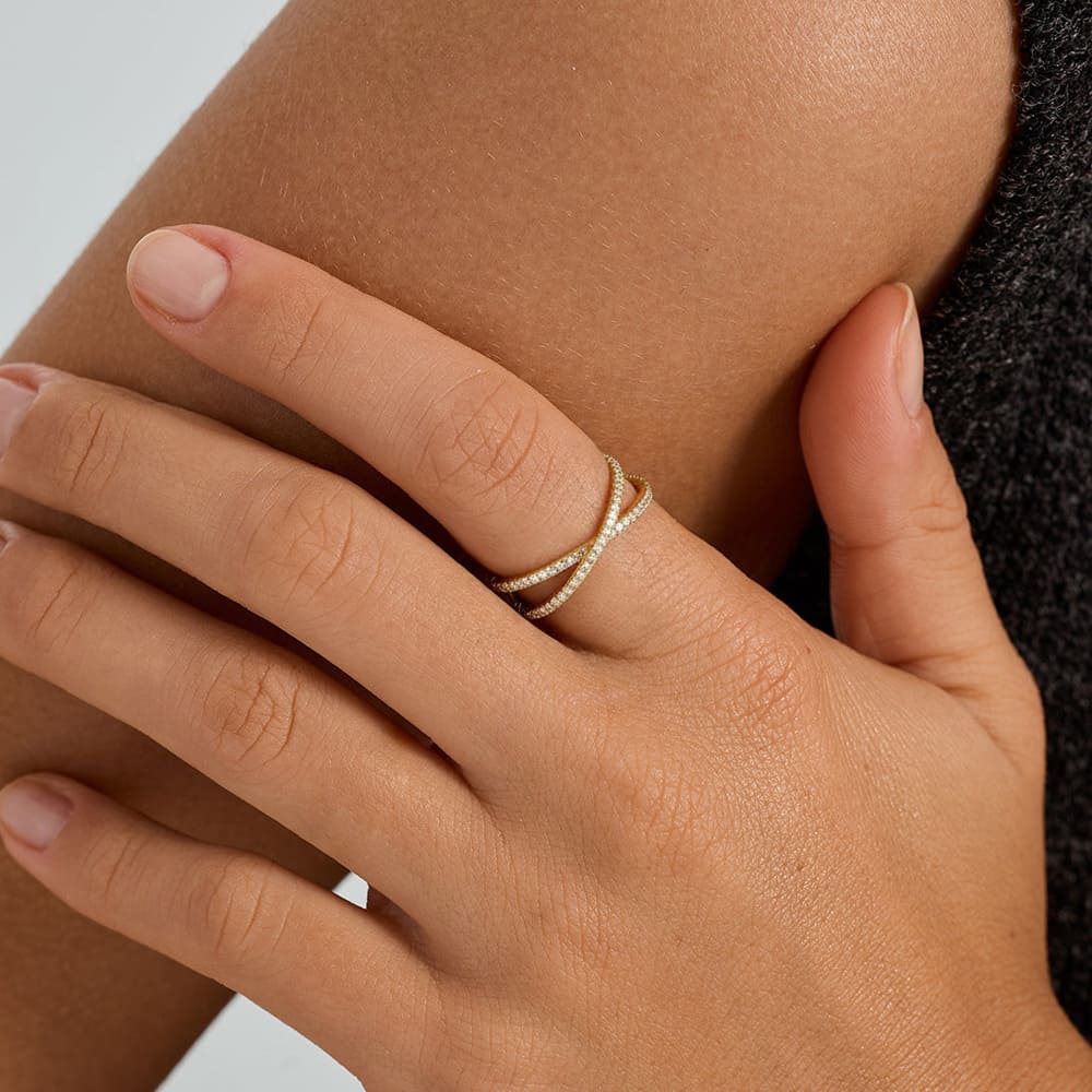 Close-up of a hand wearing a diamond ring on a neutral background