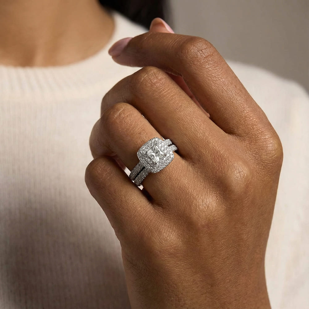 Close-up of a hand wearing a diamond ring with a neutral background