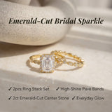 Gold ring stack set with emerald-cut center stone on a neutral background