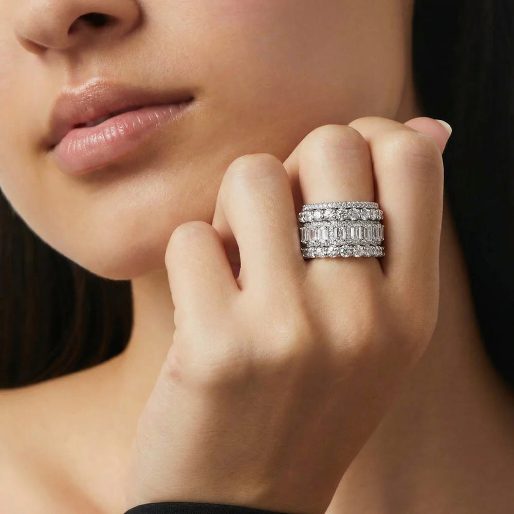 Close-up of a hand wearing multiple diamond rings with a blurred background