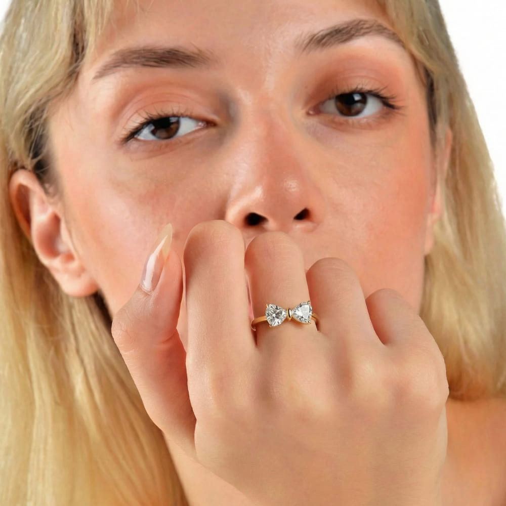 Close-up of a woman with blonde hair and a diamond ring on her finger, holding her hand to her mouth.