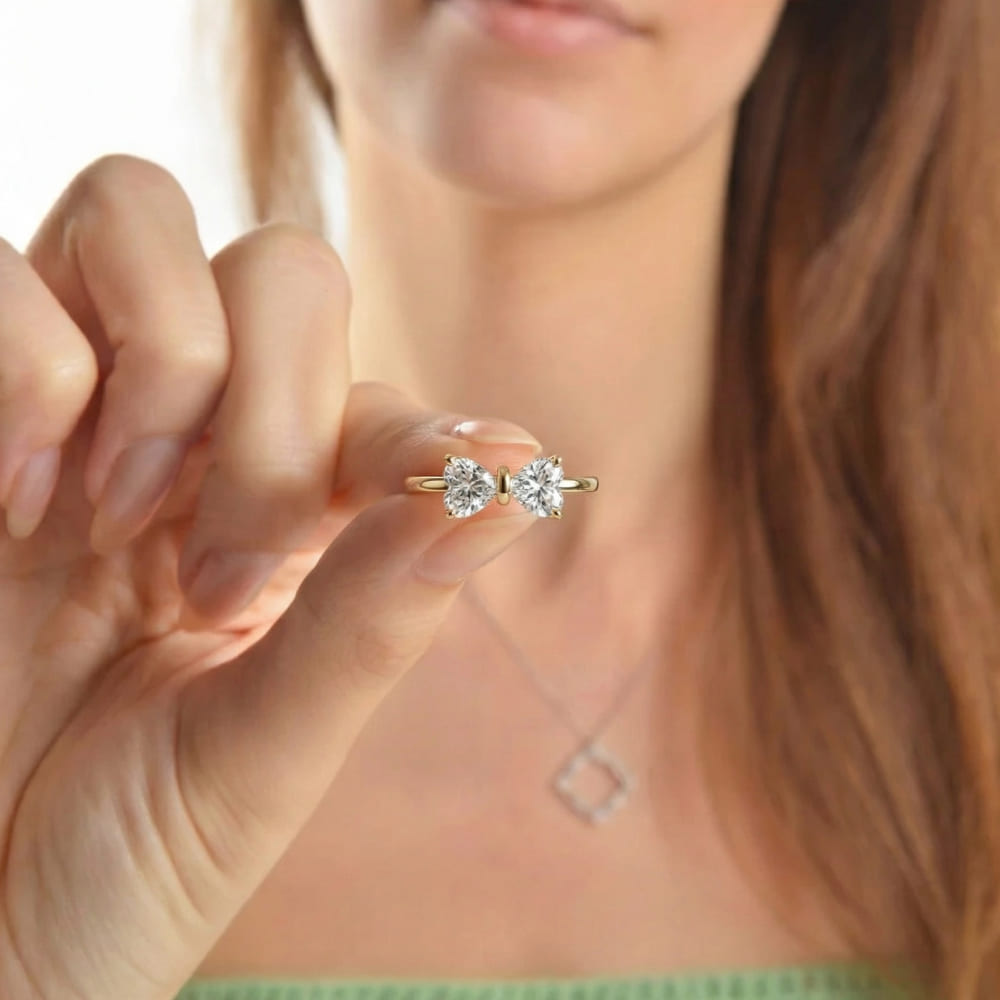 Gold and diamond earring held by a hand with a blurred background