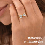 Rose gold ring with heart-shaped diamonds on a hand, labeled 'Waterproof & Tarnish-free'.