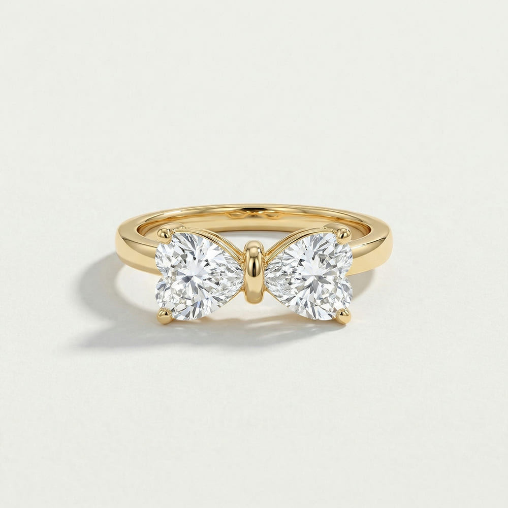 Gold ring with two large diamonds on a light beige background