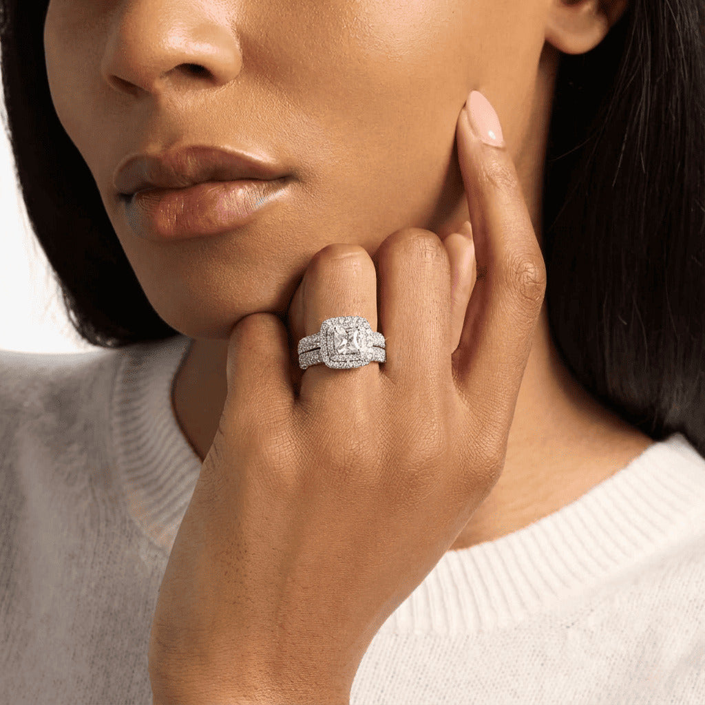 Close-up of a woman's hand wearing a diamond ring, with a neutral background.