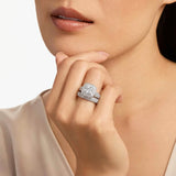Close-up of a woman's hand wearing a diamond ring with a neutral background